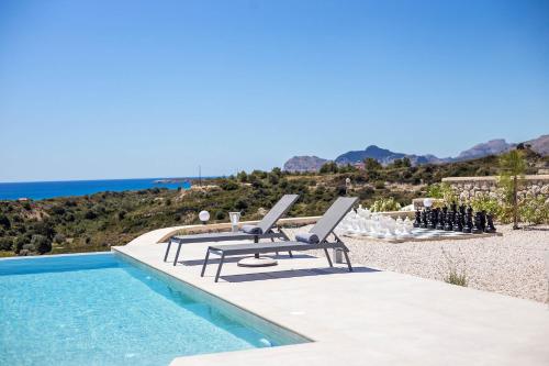 a pool with two lounge chairs and the ocean at Your House In Rhodes in Afantou