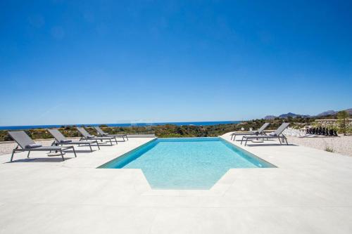 a swimming pool with lounge chairs and the ocean at Your House In Rhodes in Afantou