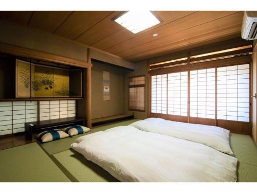 a bedroom with a white bed in a room with windows at Arbor house - Vacation STAY 86735 in Kagoshima