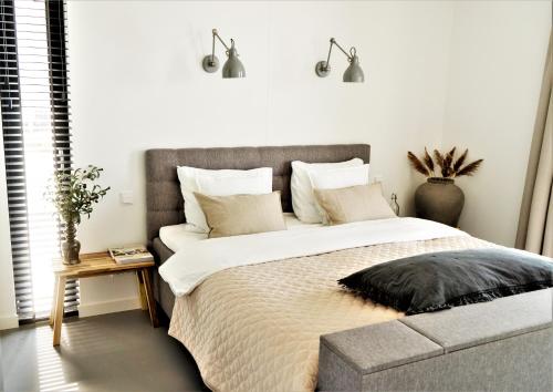 um quarto com uma cama grande e uma cabeceira cinzenta em B&B Ganzendiep aan het water em Grafhorst