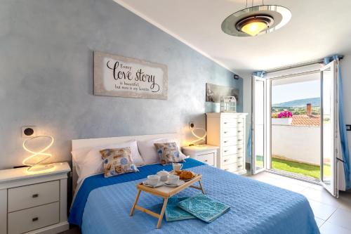 een slaapkamer met een bed met een blauwe sprei en een tafel bij Sunset Bay Tecno Home Sardinia in Valledoria