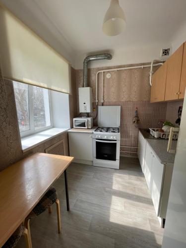 ウファにあるApartments ROMAYA Economy classの小さなキッチン(白い家電製品、木製テーブル付)