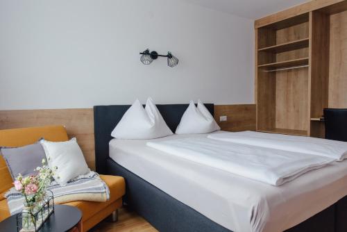 a bedroom with a white bed and a chair at Hotel Drei Kreuz - Self Check In in Salzburg