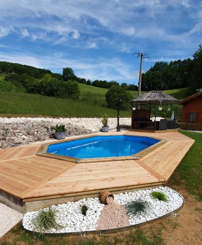 une piscine avec une terrasse en bois et un kiosque dans l'établissement Chalet charmant à Dausse avec piscine et jardin, à Dausse