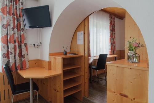 ザルツブルクにあるホテル ドライ クロイツのデスク、テーブル、椅子が備わる客室です。