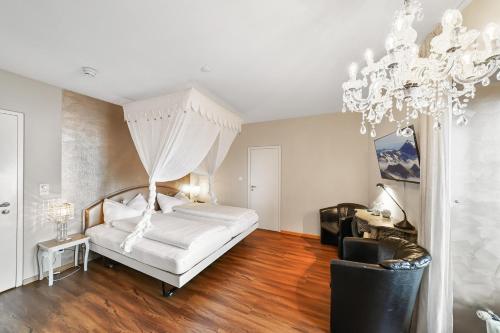 a bedroom with a white bed and a chandelier at Schloss Wartensee in Rorschacherberg