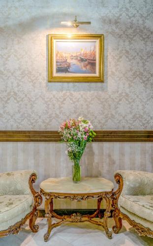 a vase of flowers on a table with two chairs at Feder Boutique Hotel in Lviv