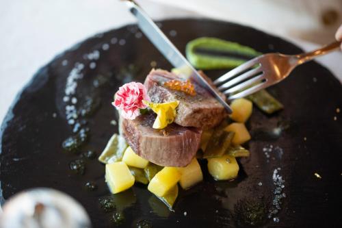 a piece of meat on a plate with a fork at Laguna Palace Hotel Grado in Grado