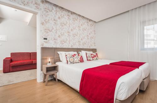 a white bedroom with a large bed with a red blanket at Essence Inn Marianos Hotel in Fátima