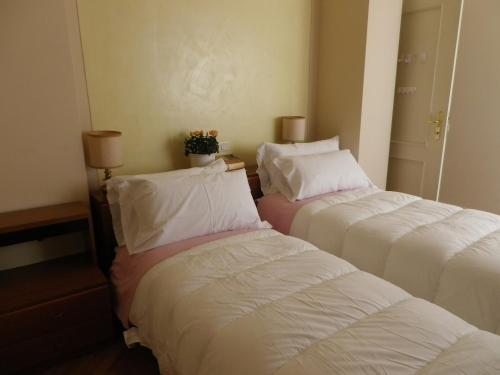 due letti in una camera d'albergo con lenzuola bianche di La Terrazza a Lucca