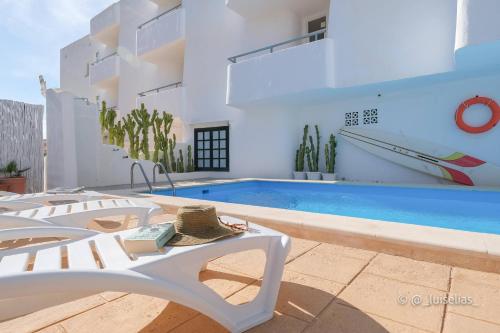 a villa with a swimming pool and two chairs at Apartamentos Ibiza in Colònia de Sant Jordi