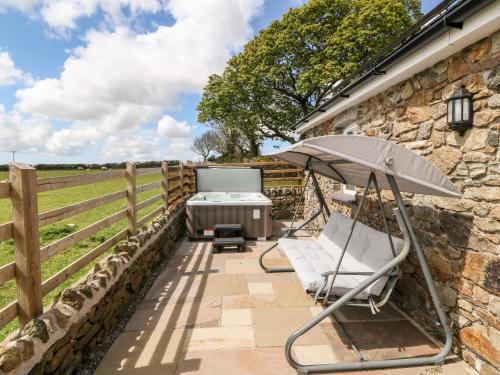 a patio with a table and an umbrella at Beudy Tyddyn in Llandyfrydog