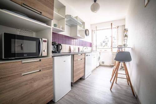 La cuisine est équipée d'un réfrigérateur blanc et d'un four micro-ondes. dans l'établissement Le Petit Joyau - 1 Chambre, à Brive-la-Gaillarde