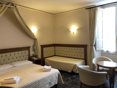 a hotel room with two beds and a table at Hotel Le Due Fontane in Florence