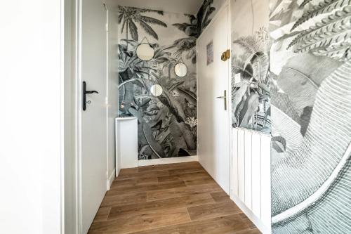 un couloir orné d'une fresque murale représentant des plantes sur les murs dans l'établissement Le Cocon Urbain - 1 Chambre, à Brive-la-Gaillarde