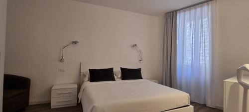 a bedroom with a white bed and a window at RivAppartamenti in Riva del Garda