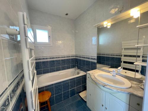 La salle de bains est pourvue de carrelage bleu, d'un lavabo et d'une baignoire. dans l'établissement Les forestiers 2, à Mimizan