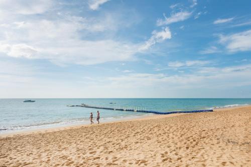 two people walking on the beach near the ocean at The Waters Khao Lak by Katathani - SHA Extra Plus in Khao Lak