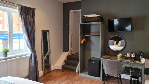 a room with a desk and a staircase with a mirror at The George Inn in Barton-upon-Humber