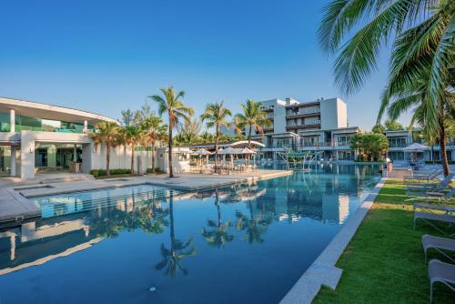 a swimming pool with palm trees and a building at The Waters Khao Lak by Katathani - SHA Extra Plus in Khao Lak