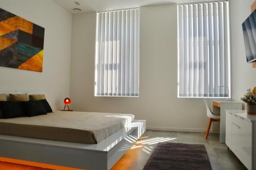 a bedroom with a bed and two windows at Bogáthy Kúria Business Apartments in Nyírbogát