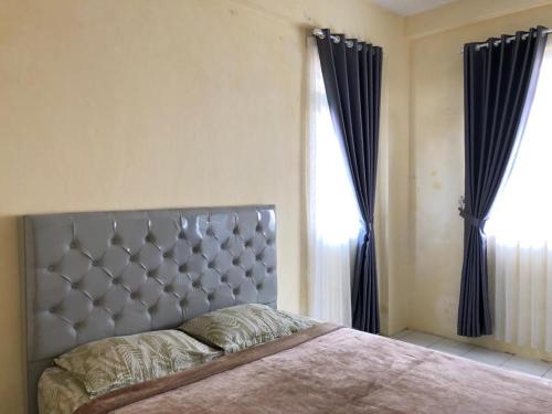 a bedroom with a large bed with black curtains at Comfy Emerald Hill Karawang in Telukjambe