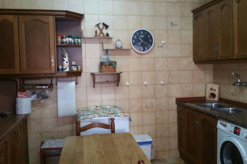 eine Küche mit einem Tisch und einer Uhr an der Wand in der Unterkunft CASA NOGALES junto a PLAYA DE POO y SENDA. WIFI in Poo de Llanes