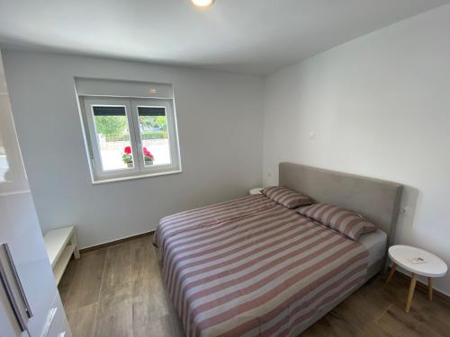 a small bedroom with a bed and a window at Apartman Terra in Medulin