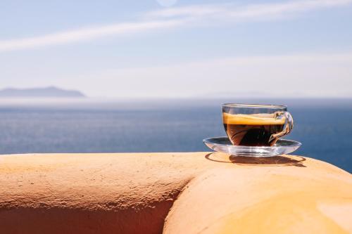 a cup of coffee sitting on the edge of a ledge at Front Row Seat to the Aegean by Neuvel in Ioulida