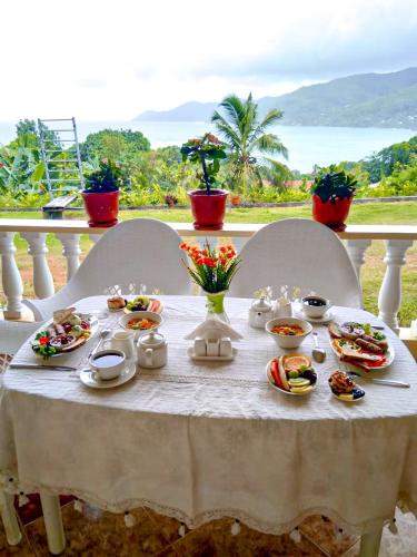 a white table with plates of food on it at SeyBreeze Villa in Anse Royale