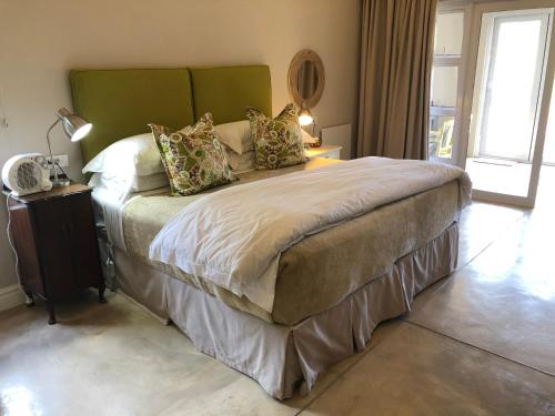 a bedroom with a large bed with a green headboard at Lavender Trout Guest Farm in Nottingham Road