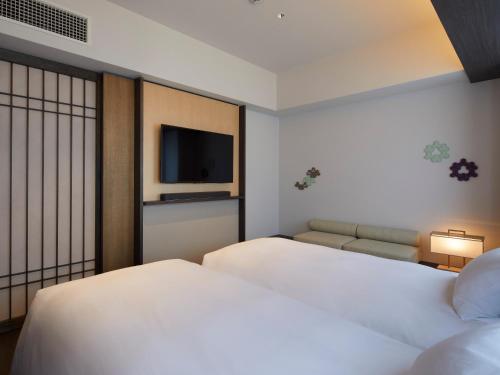 a hotel room with two beds and a flat screen tv at Agora Kyoto Shijo in Kyoto
