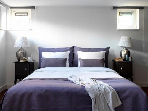 a bedroom with a bed with purple sheets and pillows at Watervilla in Loosdrecht