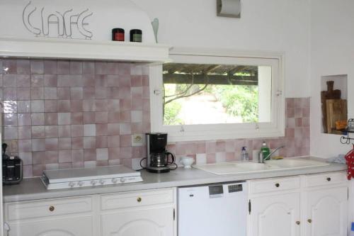 a kitchen with a sink and a window at Grande maison au cadre verdoyant au centre village in Cargèse