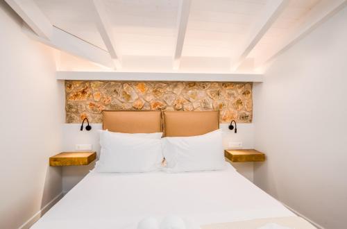 a bedroom with a white bed with two benches at Bella Terra Houses in Roda