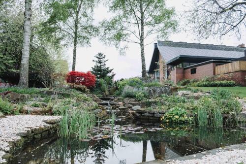 a garden with a pond in front of a house at Edgbaston Park Hotel Birmingham in Birmingham