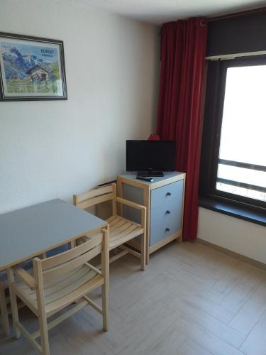 - un salon avec une table, une télévision et un bureau dans l'établissement La Voile - Pendine 2 - Puy Saint Vincent - Hautes Alpes, à Puy-Saint-Vincent
