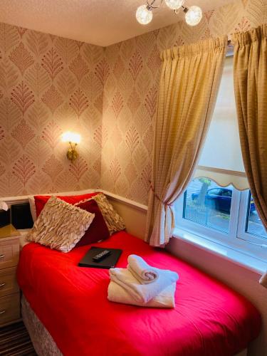 a red bed in a room with a window at Fairfax in Skegness