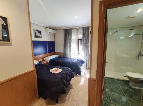 a hotel room with two beds and a shower at Trípolis Toledo in Toledo