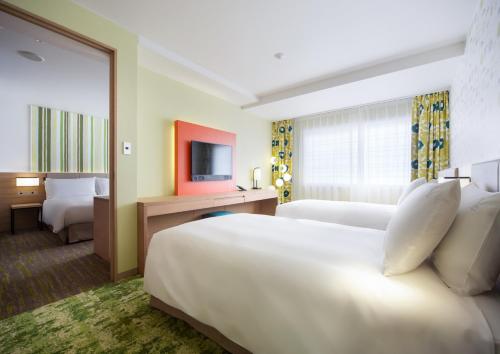 a hotel room with two beds and a television at Holiday Inn Resort Shinano-Omachi Kuroyon by IHG in Omachi