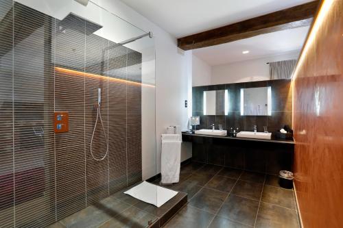 a bathroom with two sinks and a shower with a glass door at Château de Melin - B&B in Auxey-Duresses