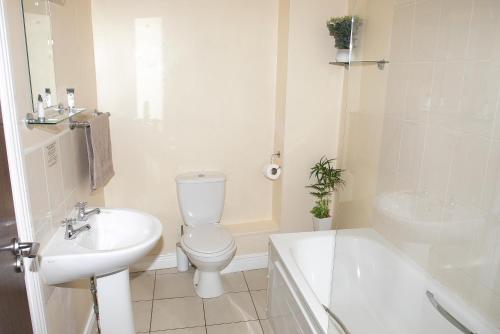 a white bathroom with a toilet and a sink at Arch House Apartments in Athlone