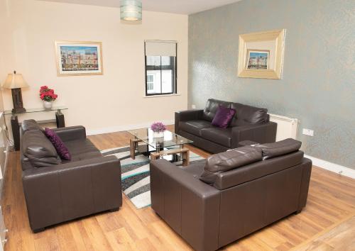 a living room with two leather couches and a table at Arch House Apartments in Athlone