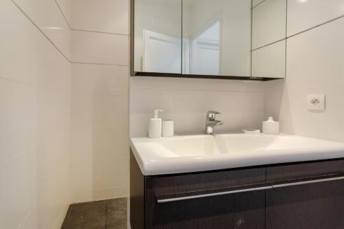 une salle de bain avec un lavabo blanc et un miroir dans l'établissement Maison Morny, à Deauville