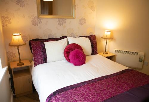 a bed with a pink pillow on top of it at Arch House Apartments in Athlone