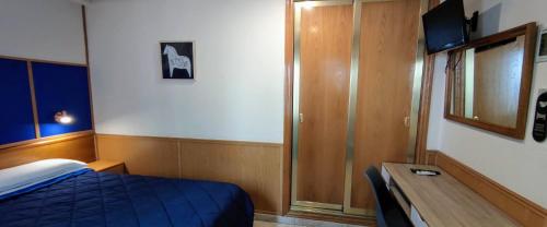Un dormitorio con una cama, un escritorio y un televisor. en Trípolis Toledo, en Toledo