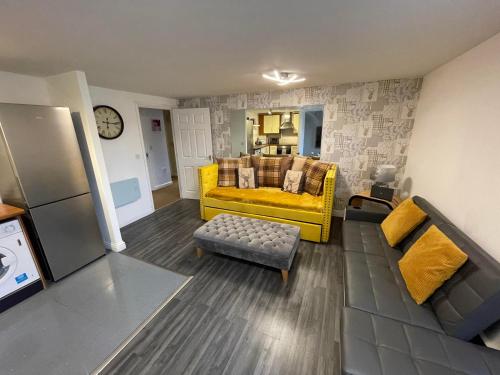 a living room with a yellow couch and a chair at Empire Serviced Apartments in Hinckley