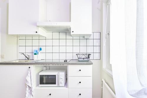 uma cozinha com armários brancos e um micro-ondas em Folkarbo Vandrarhem em Avesta