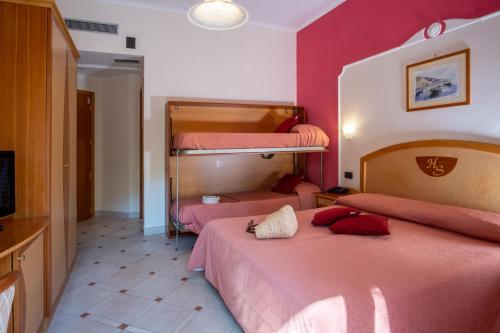 two beds in a room with pink walls at Hotel Savoia Sorrento in Sorrento
