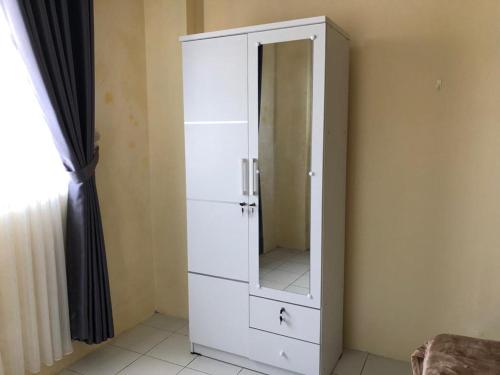 a white cabinet with a mirror in a room at Comfy Emerald Hill Karawang in Telukjambe